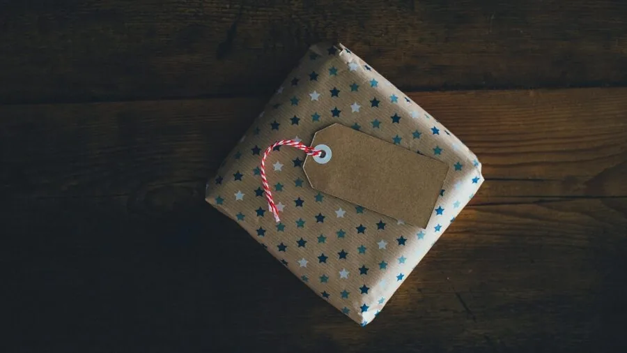 Beautifully wrapped luxury gift box with elegant ribbon and packaging on neutral surface