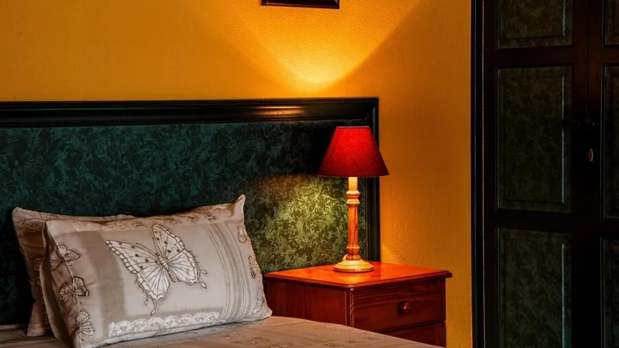 Bedroom with matching pair of lamps on wooden nightstands flanking an unmade bed
