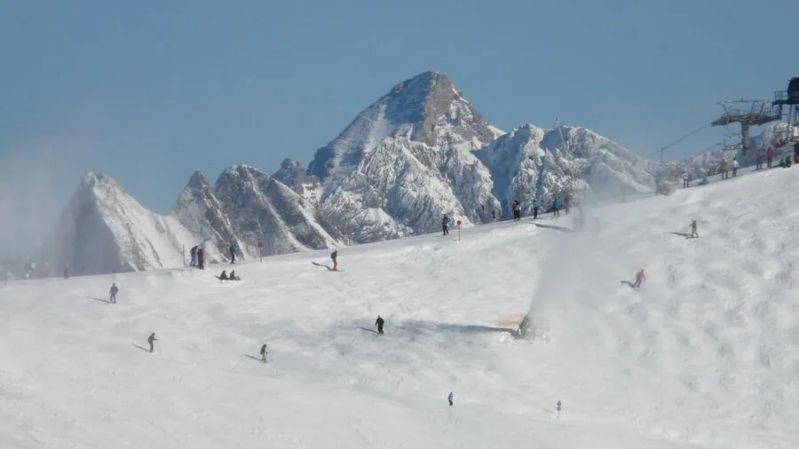 Beginner snowboarder practicing on gentle slope with instructor guidance in snowy mountain landscape