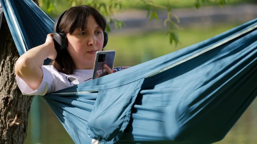 Camper relaxing in a nylon hammock strung between trees in a forest setting