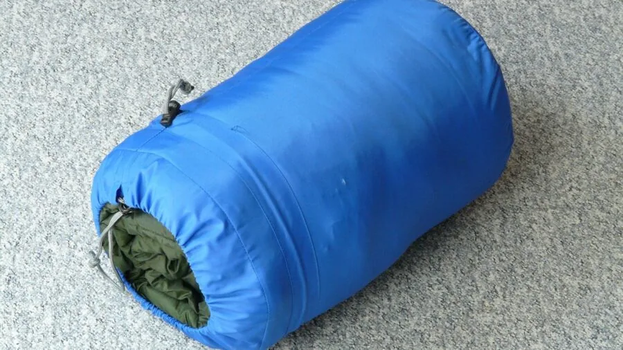 Camper resting head on pillow inside sleeping bag during outdoor camping trip