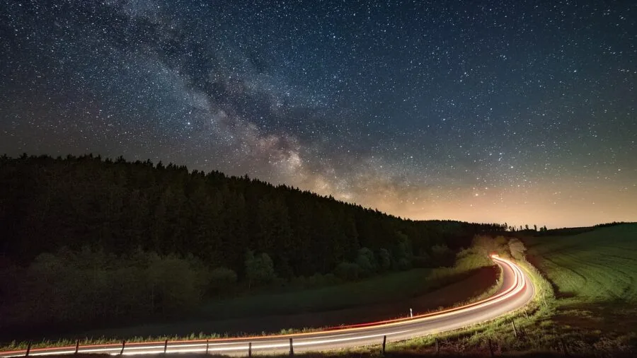 Car headlights illuminating dark road at night, demonstrating light reflection and visibility in low-light driving conditions