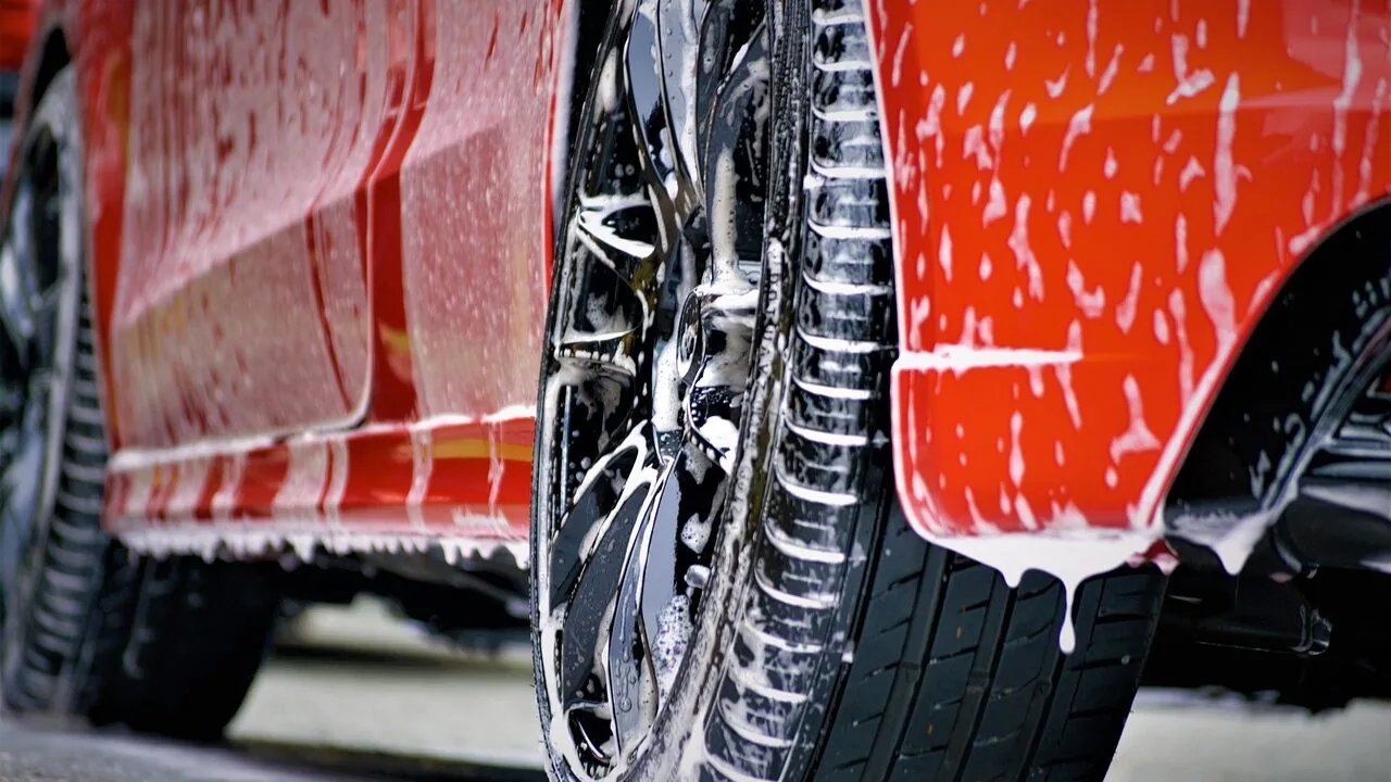 Car shampoo bottle with soapy water on car hood during washing
