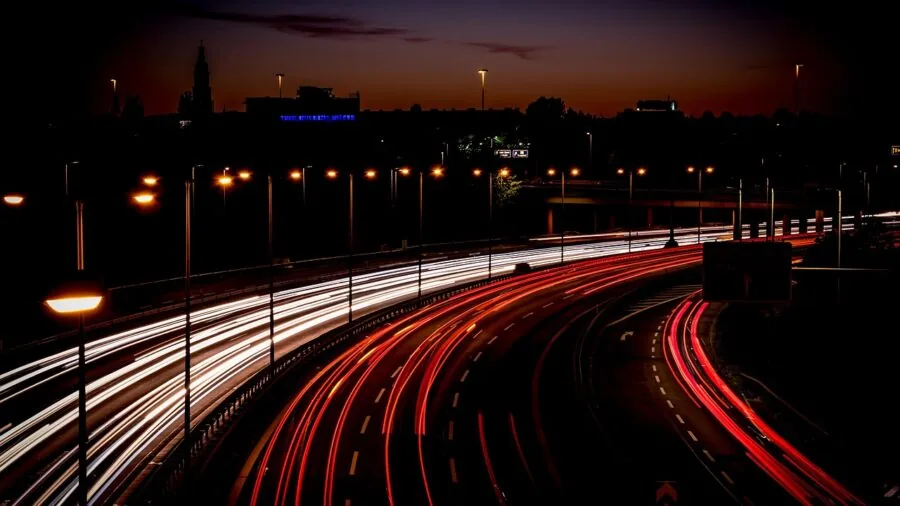 Car with hazard lights on dark highway at night for safety visibility