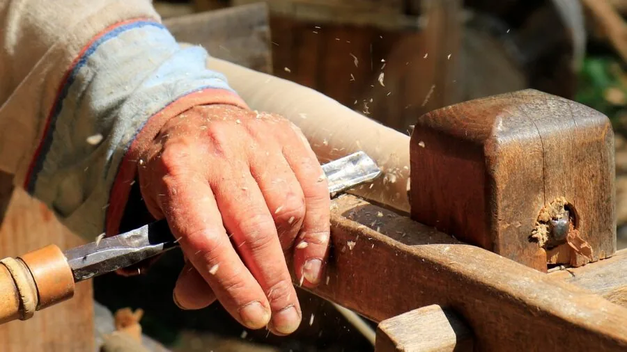Carpenter striking a metal pry bar with a hammer during construction work