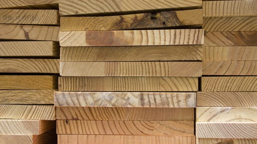 Carpenter using power tools to frame wooden deck structure outdoors in natural daylight