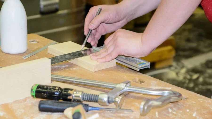 Carpenter using tape measure on wooden surface in workshop