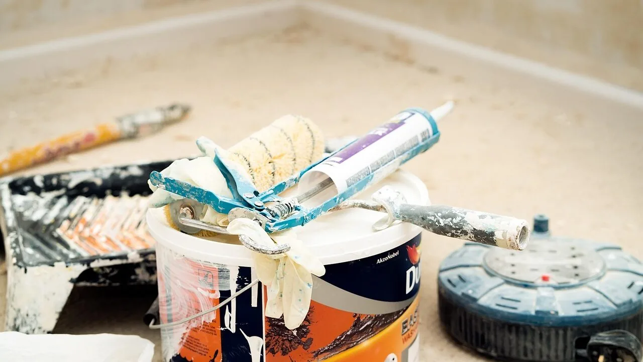 Caulking gun in use applying sealant to surface with trigger mechanism visible