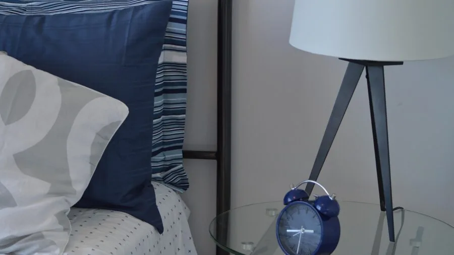 Ceramic bedside lamp on wooden nightstand in modern bedroom with soft lighting and home decor