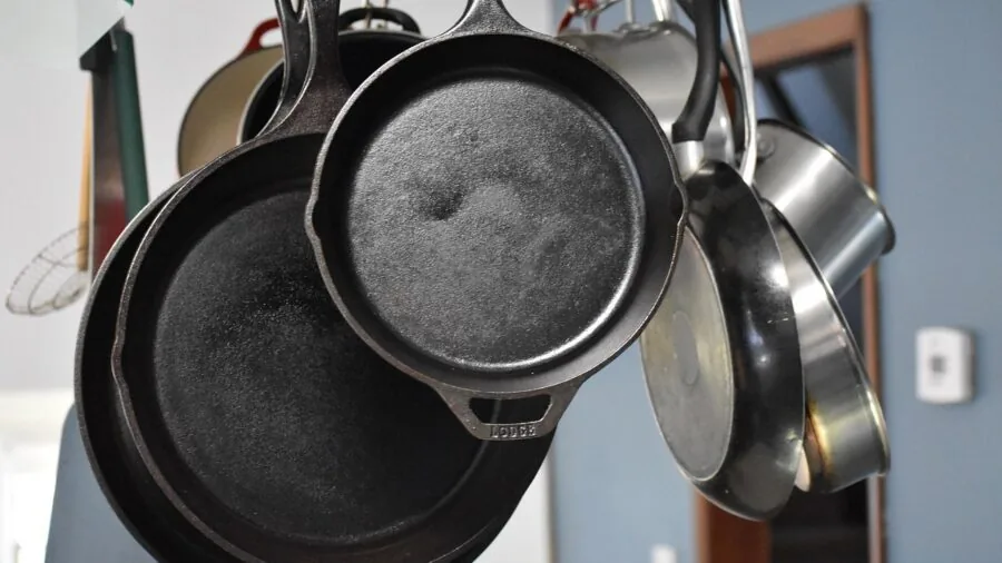 Chef cooking with cast iron griddle pan on stovetop in modern kitchen