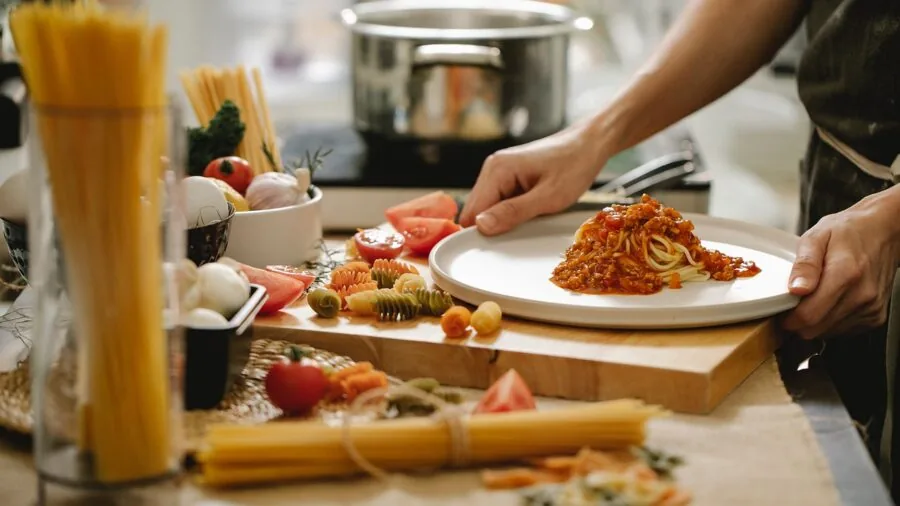 Chef preparing food in large cooking pot on stovetop in home kitchen