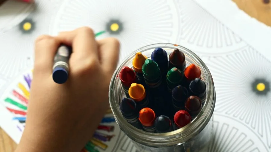 Child engaged in creative craft activity with colorful art materials on a table