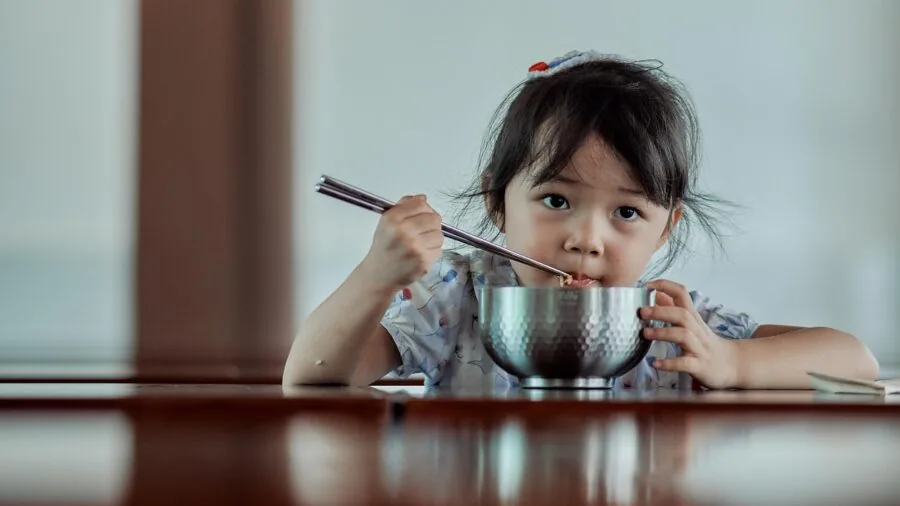 Child enjoying lunch with separated food compartments in containers