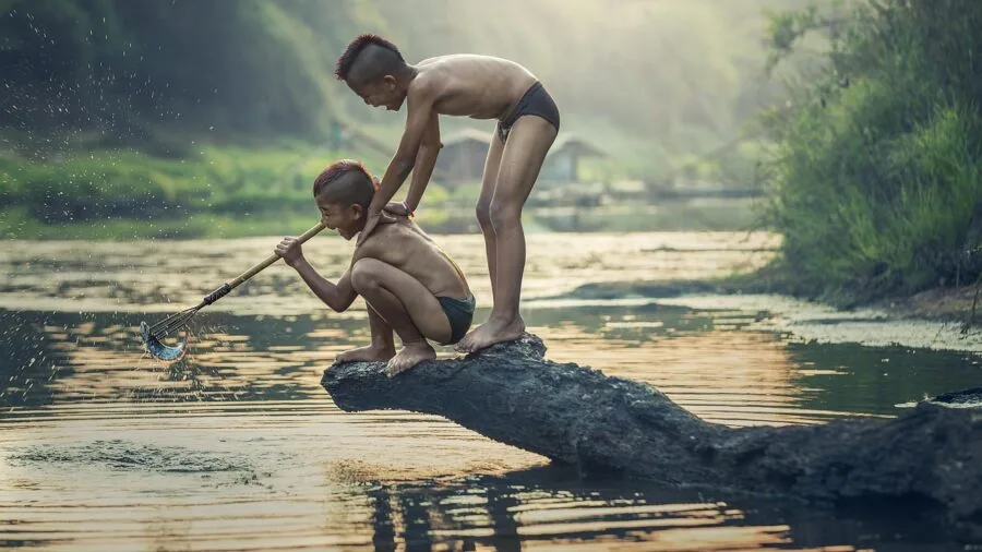 Child holding fishing rod by water during outdoor fishing adventure