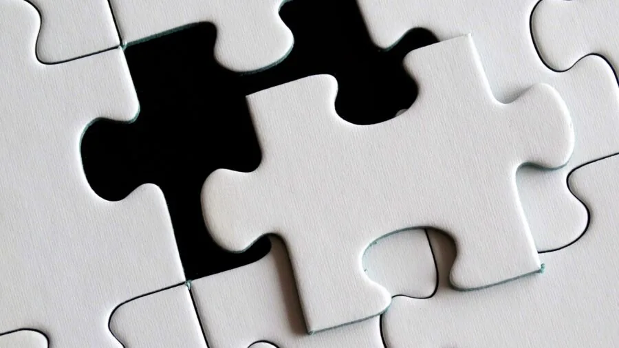 Child sorting and organizing colorful puzzle pieces into a storage container on wooden table