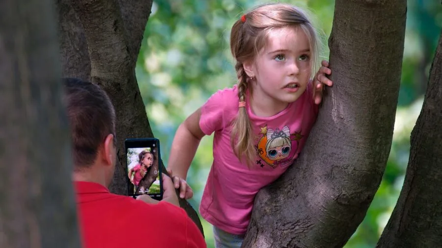 Child using smartphone to capture celestial photos through telescope at night