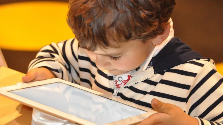Child viewing tablet screen in car backseat during road trip