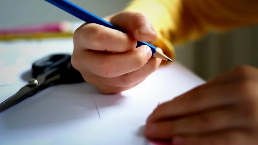 Child with backpack drawing in sketchbook at outdoor table