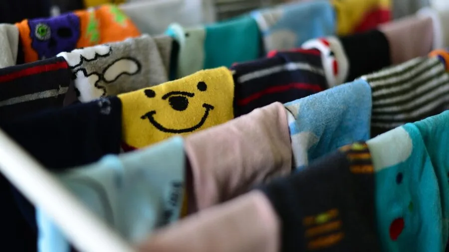 Child's laundry basket overflowing with colorful clothes and socks ready for washing