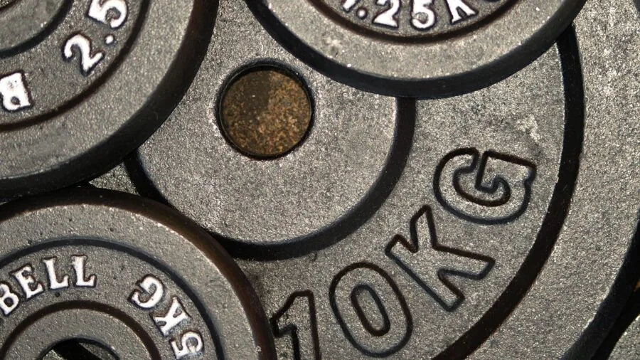 Clean gym floor with organized weight plates stacked neatly near equipment setup