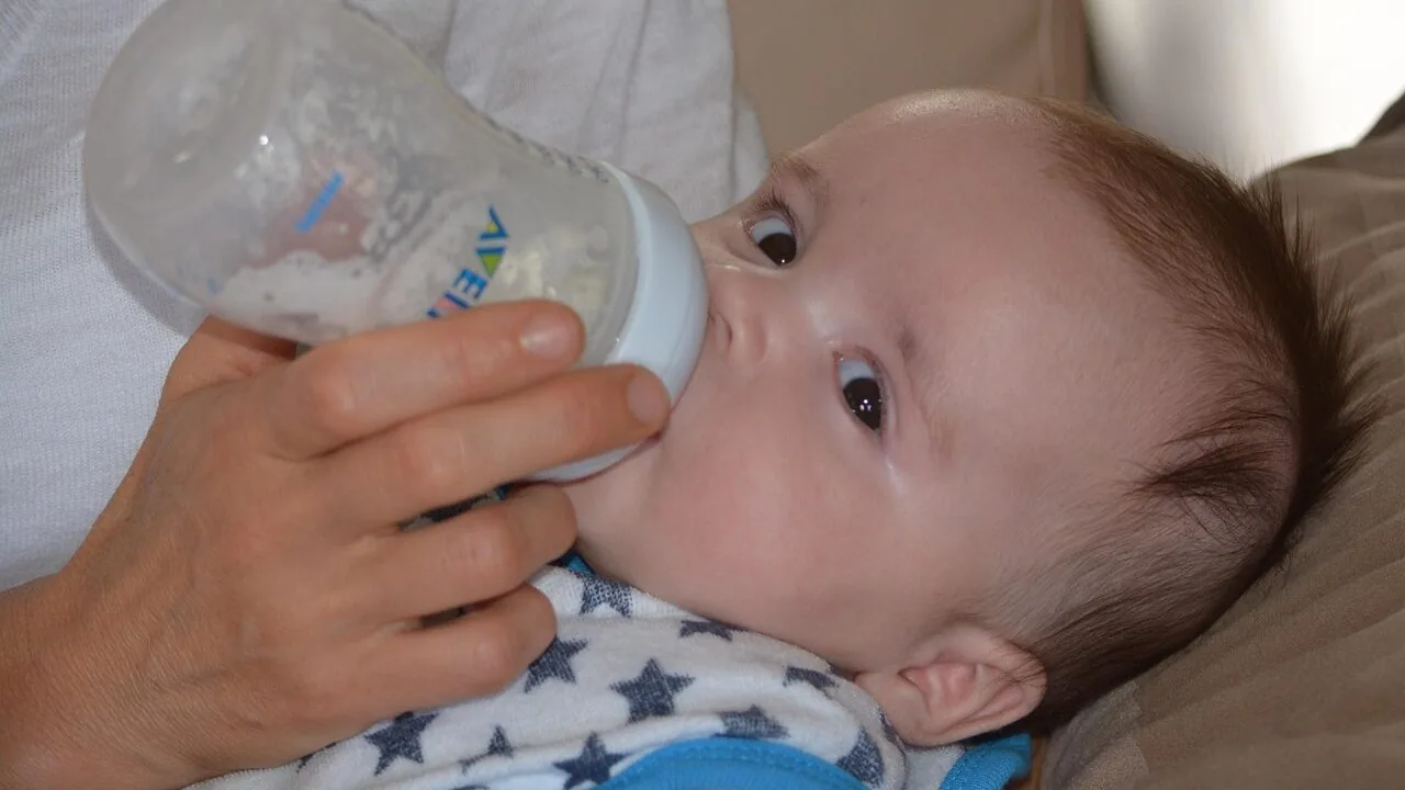 Clear glass baby bottles filled with milk on white surface
