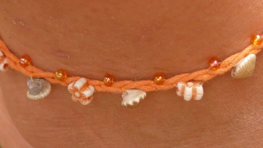 Close-up of a delicate chain anklet on a woman's ankle in natural daylight