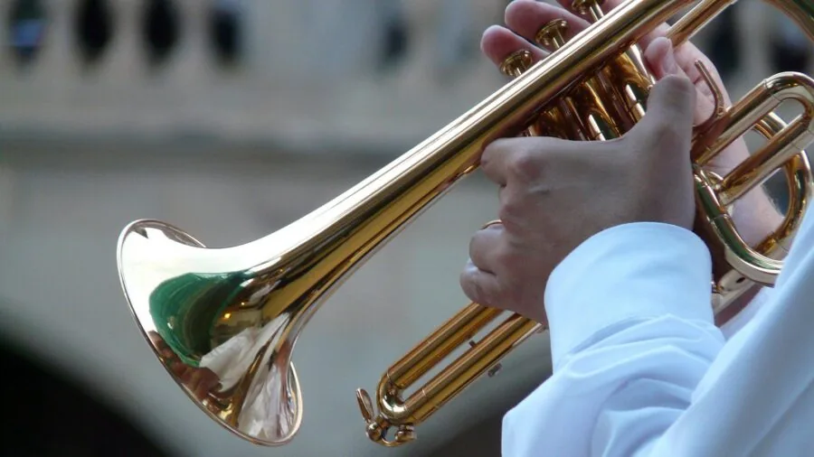 Close-up of a musician's hands playing a brass trumpet, demonstrating proper technique and instrument handling.