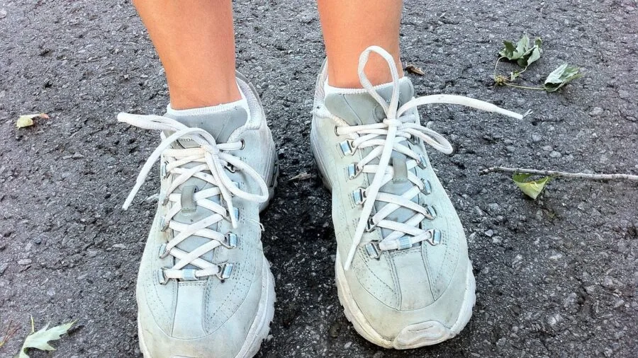 Close-up of a person adjusting their running shoes before heading out for a jog on a sunny day