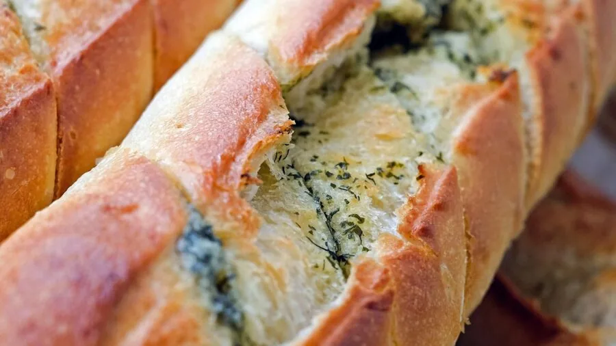 Close-up of a serrated knife cutting through fresh bread, showing the texture and crumb detail