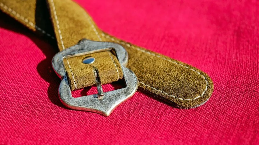 Close-up of a woman adjusting her belt buckle, showing the metal hardware and durability of the accessory