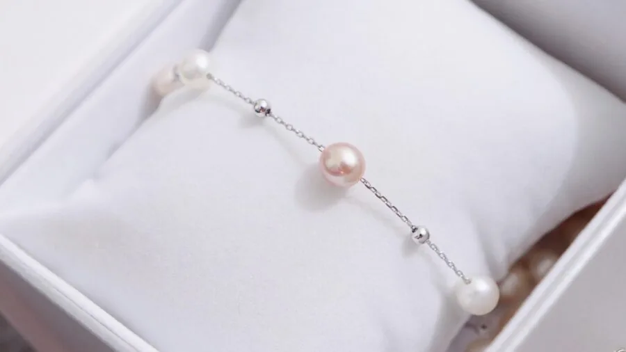 Close-up of a woman's wrist displaying a charm bracelet with detailed chain links visible