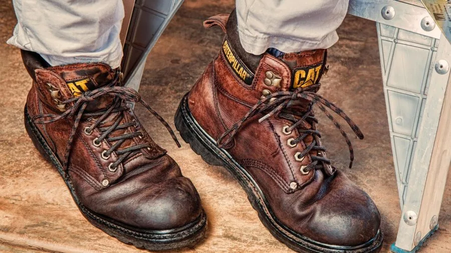 Close-up of a worker's hands wearing protective leather gloves while gripping a tool during manual work