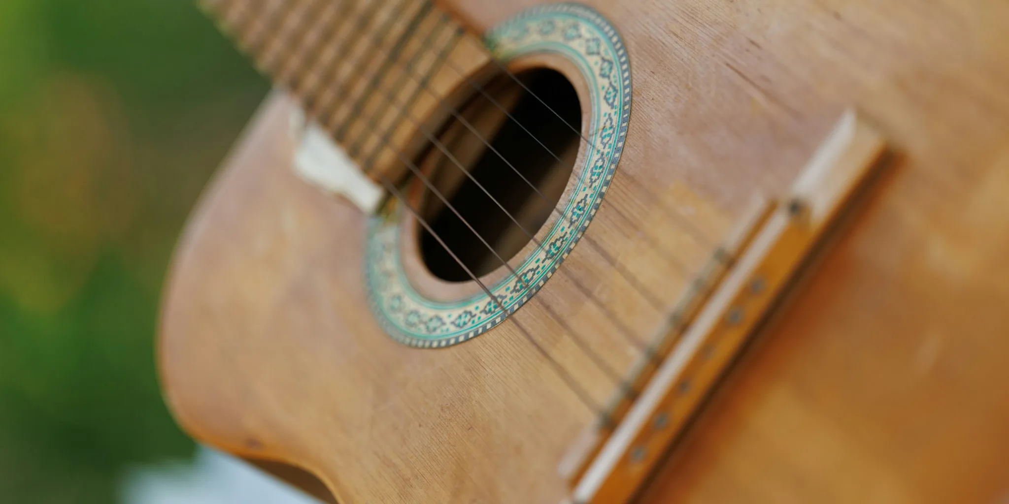 Close-up of acoustic guitar showing wooden body and strings in natural light