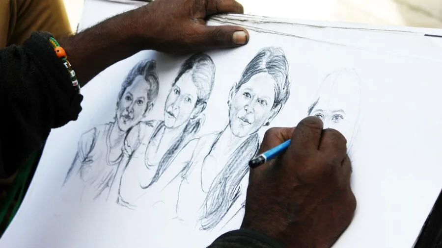 Close-up of an artist's hand sketching on textured paper with pencil, showing paper quality and weight