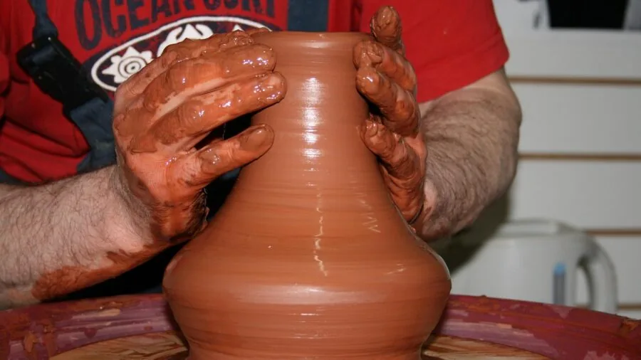 Close-up of artist hands shaping clay sculpture with focused attention to detail and texture