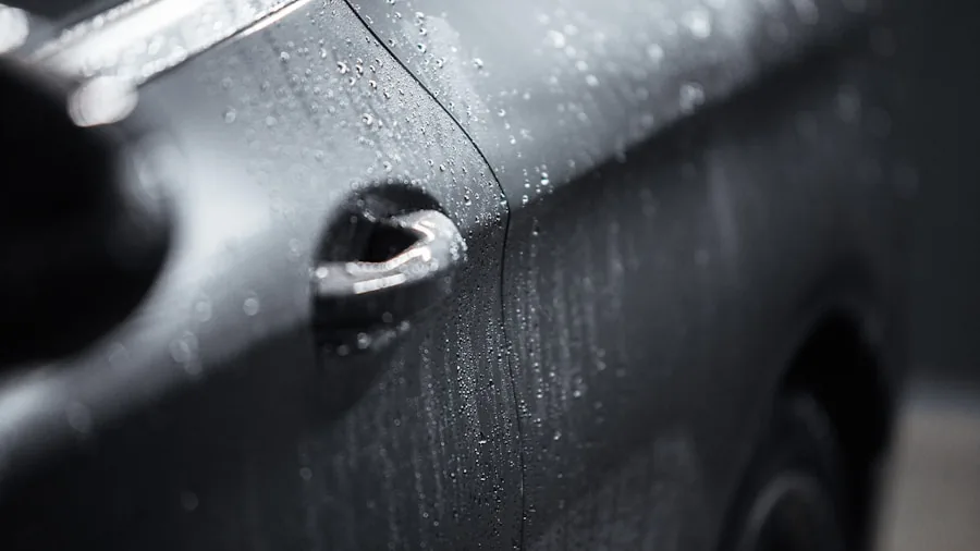 Close-up of car paint surface showing swirl marks and light scratches in natural sunlight