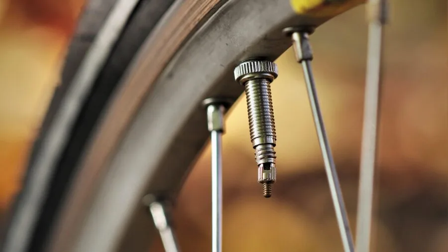 Close-up of cyclist examining bike tire valve during maintenance check