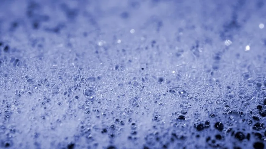Close-up of dense, fluffy white bubbles in a relaxing bathtub during a spa soak