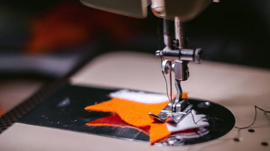 Close-up of fabric being sewn on a serger machine during active stitching