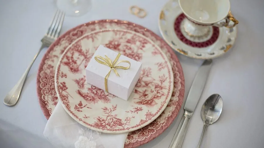 Close-up of fine porcelain dinnerware arranged on a wooden dining table with natural lighting