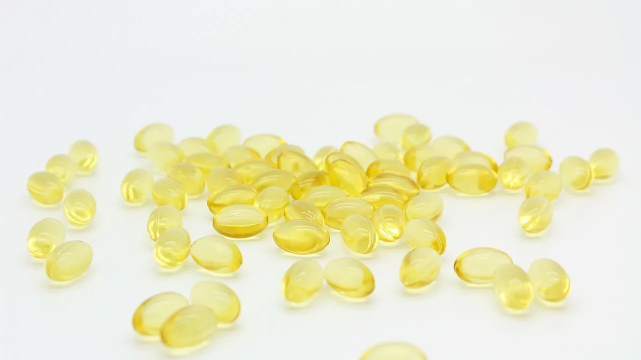 Close-up of fish oil supplement capsules and bottles on white background