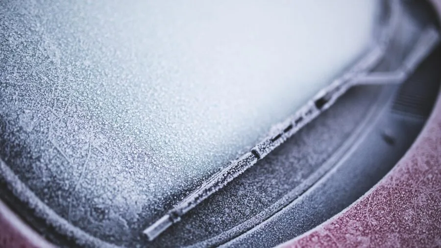 Close-up of frost-covered car windshield in winter weather showing ice crystal texture and buildup