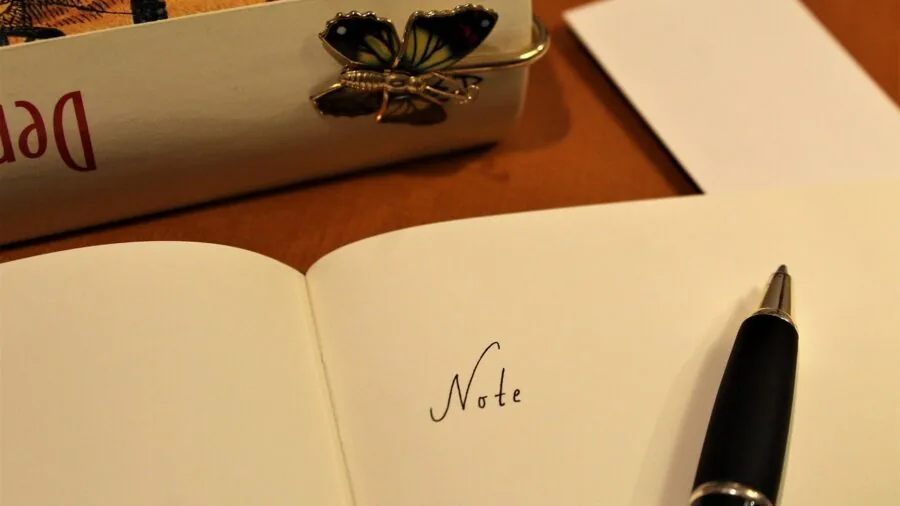 Close-up of hand writing on paper with pen, showing handwriting detail and line width variation