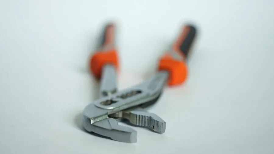 Close-up of hands adjusting a tool's grip mechanism during repair work
