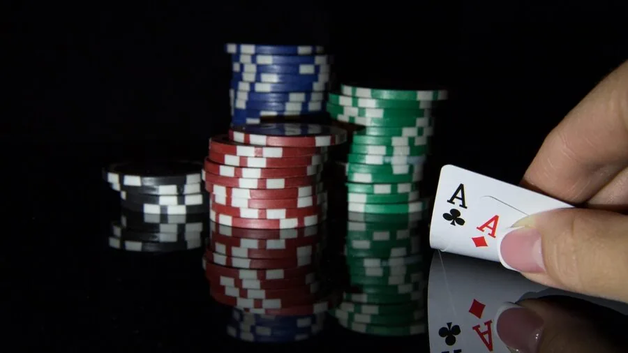 Close-up of hands carefully stacking poker chips on a gaming table during play