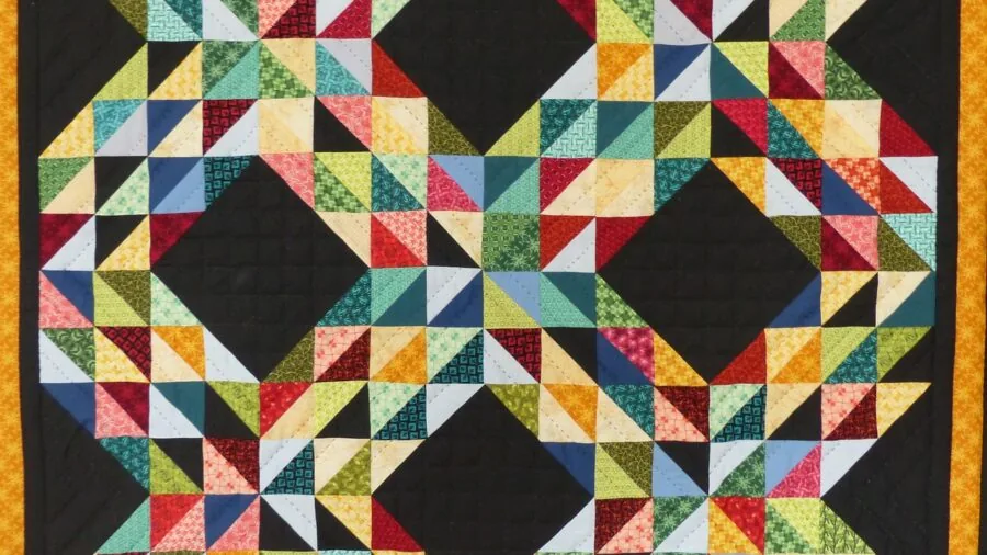 Close-up of hands carefully stitching quilt fabric with needle and thread