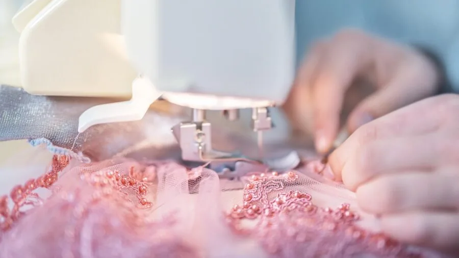 Close-up of hands carefully threading a serger machine during setup