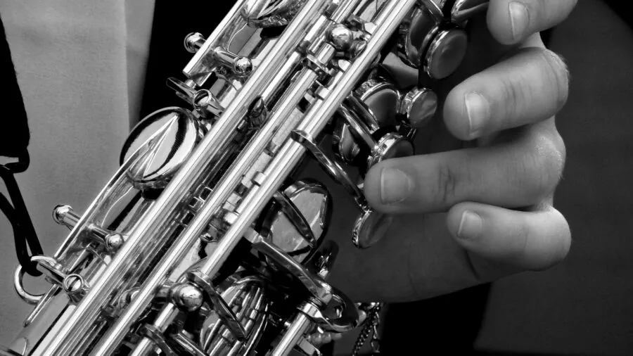 Close-up of hands examining brass saxophone materials and construction quality in natural lighting