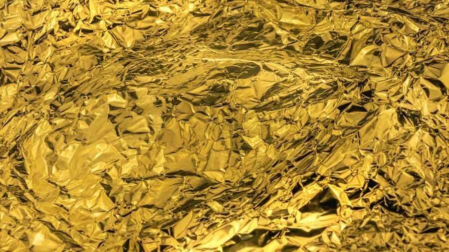 Close-up of hands examining polished gold metal surface in natural light