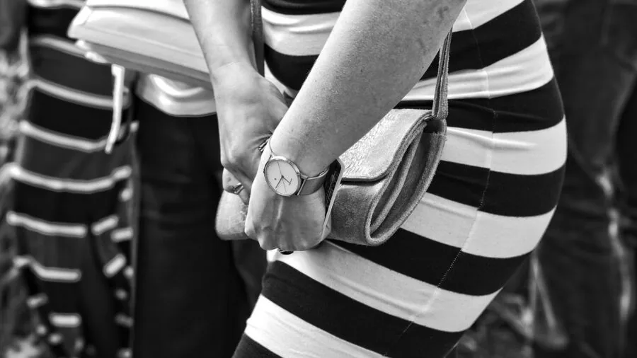 Close-up of hands fastening a leather watch strap buckle in natural daylight